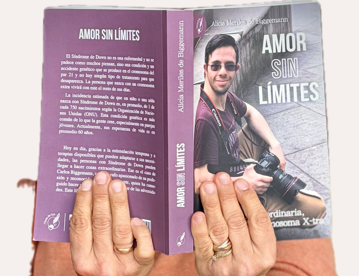 El libro abierto, sostenido con las dos manos: se ven la contratapa, el lomo y la tapa.
